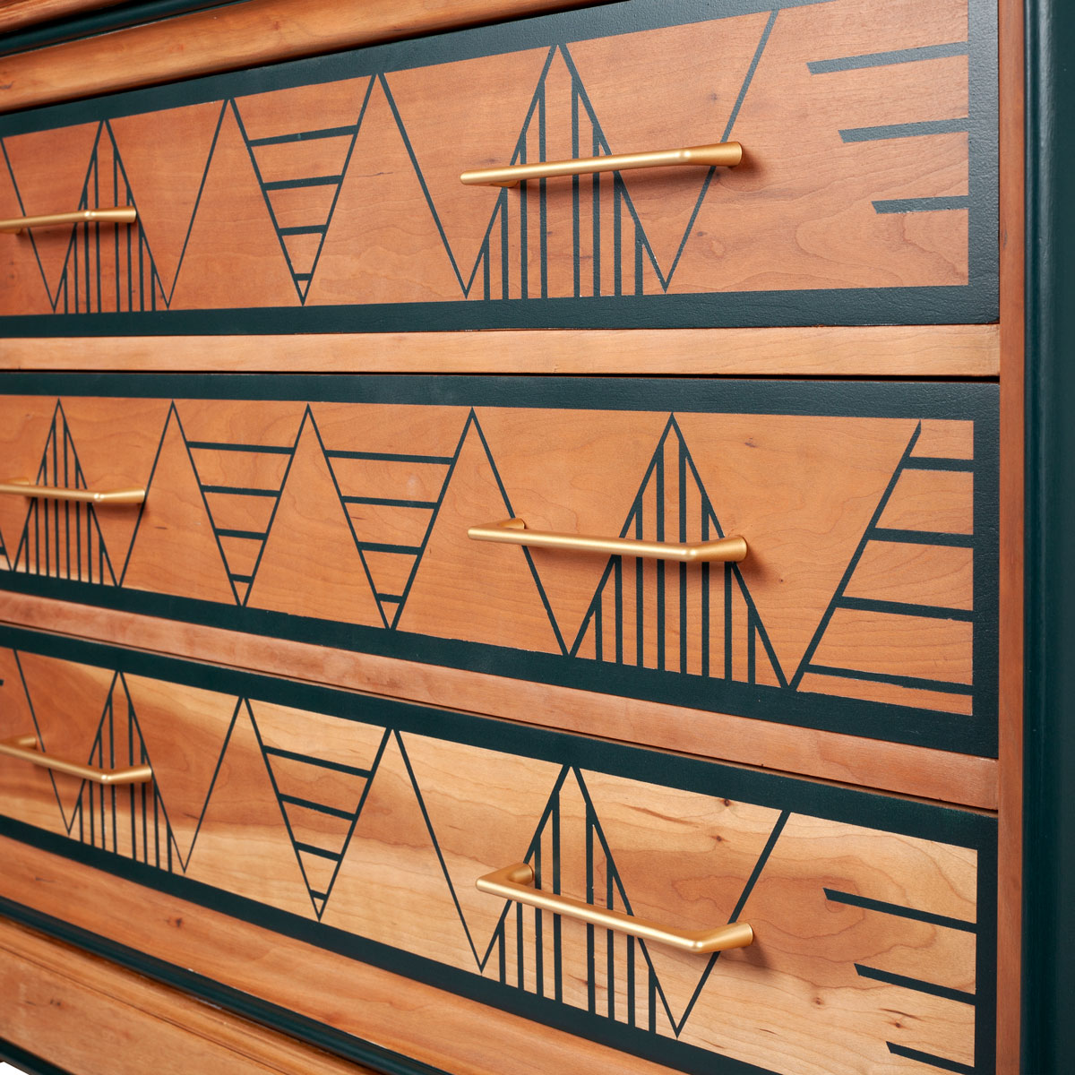 détail motifs tiroirs commode 3 tiroirs vert relookée. Les tiroirs ont gardé l'aspect bois et le motif est peint en vert